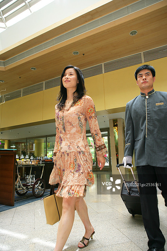 年轻女士和服务生在酒店大堂行走图片素材