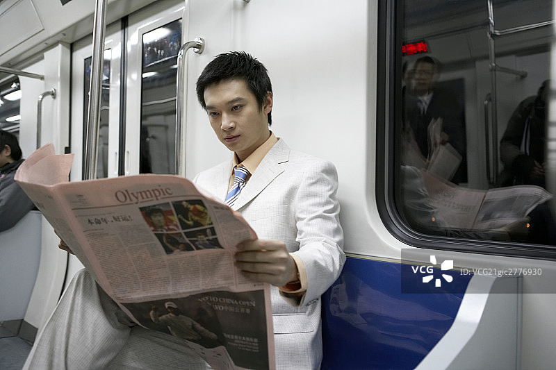商务男士在地铁里看报纸图片素材