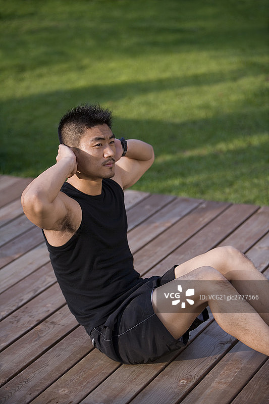 年轻男子做仰卧起坐图片素材