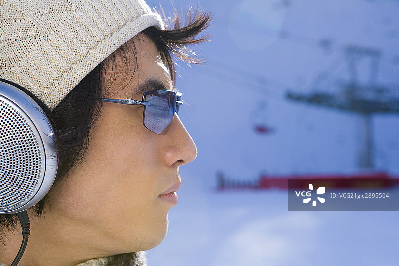 雪地上听音乐的年轻男子图片素材