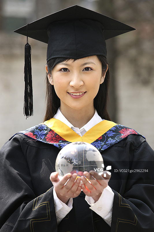 东方女孩身穿博士服手捧水晶球图片素材