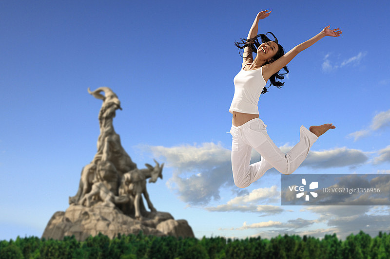 东方女人在五羊石像跳跃图片素材