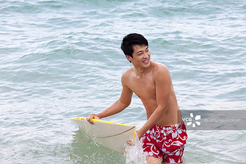 拿着冲浪板的男孩在海里图片素材