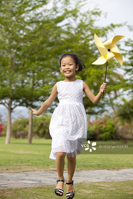 女孩拿着风车在草地上奔跑图片素材