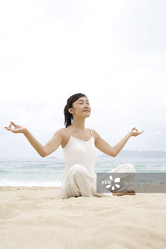 女子海边瑜珈盘腿展开双手图片素材