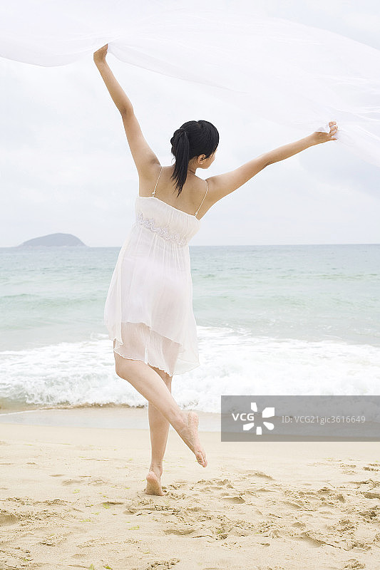 女子海边起舞双手扬纱图片素材