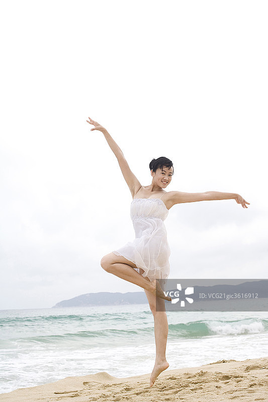 女子海边起舞单腿立展臂图片素材