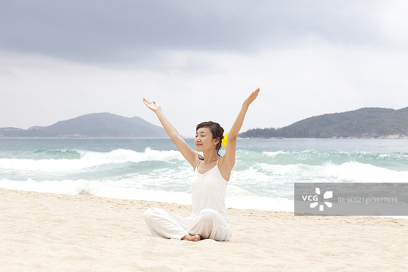 女子海边瑜珈盘腿展开双手图片素材