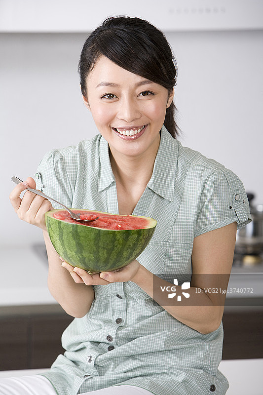 青年女子在厨房吃西瓜图片素材