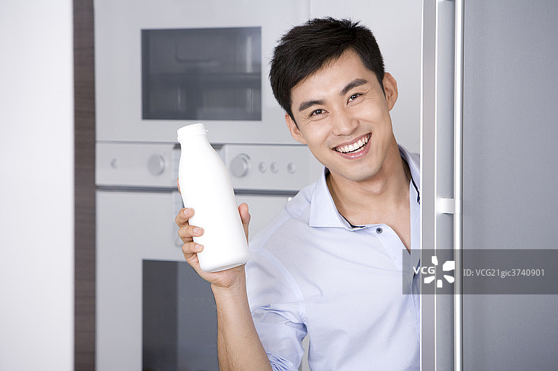 青年男子从冰箱拿出牛奶图片素材