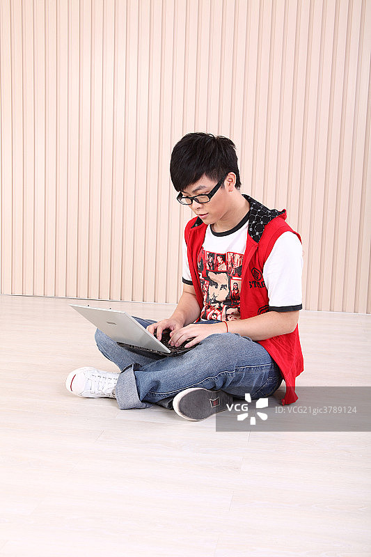 坐在地板上用笔记本的男孩图片素材