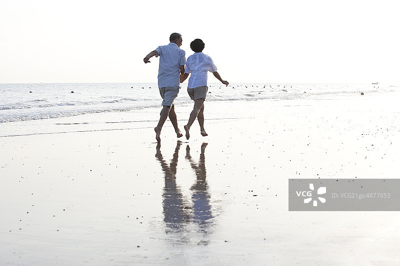 老年夫妇在海边奔跑图片素材
