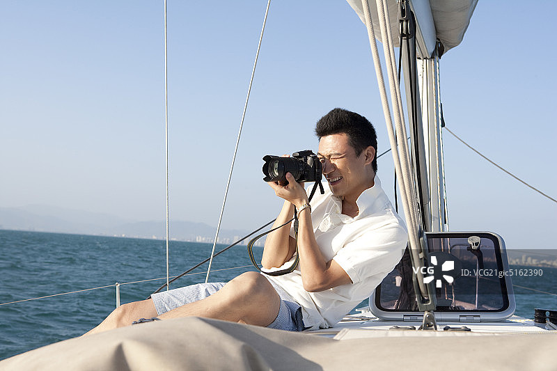青年男子在帆船上拍照图片素材