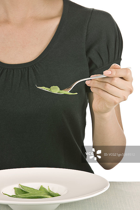 女人坐在桌旁，手持叉子，特写，中部图片素材