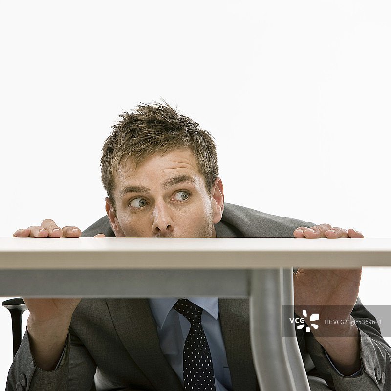 躲在桌子下的商人图片素材