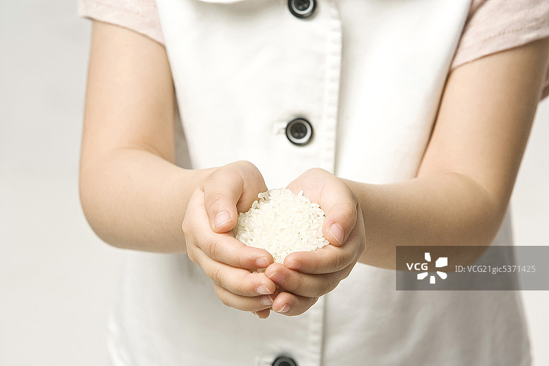 女孩手捧一把白米，特写图片素材