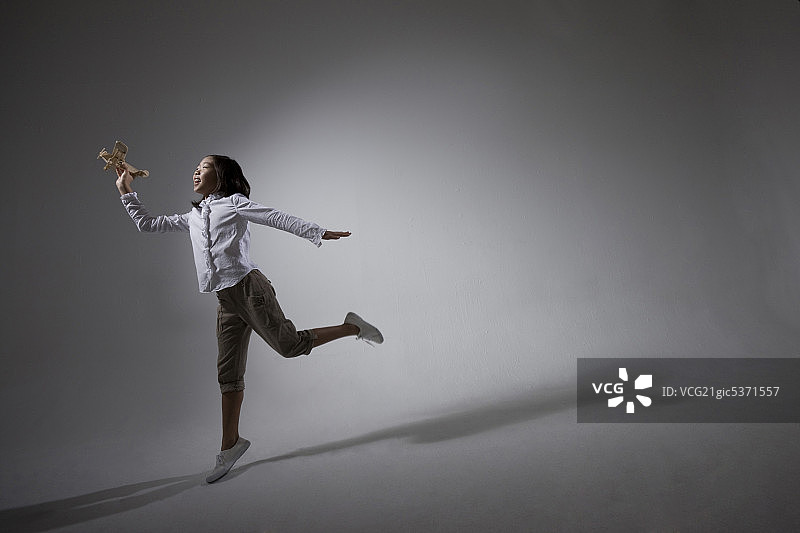 女孩手拿模型飞机，身后有影子图片素材