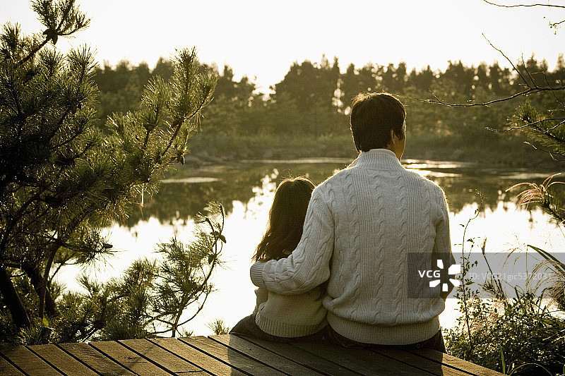父女坐在湖边，背影图片素材