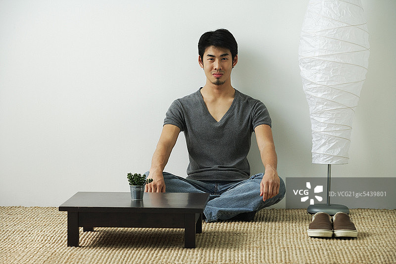 年轻男人坐在地板上，看着镜头图片素材