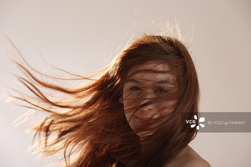 年轻的亚洲女孩，长发在风中飘扬图片素材