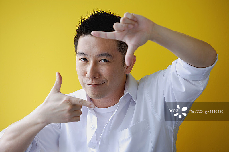 男人用手指做取景框，看着镜头图片素材