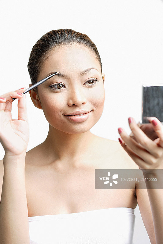 年轻女人使用眉刷看粉饼图片素材