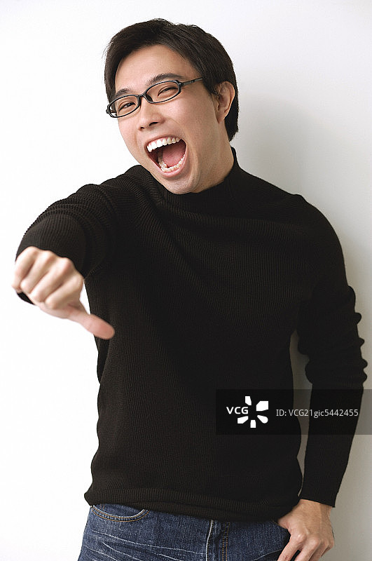 穿着黑色高领毛衣，竖起大拇指向下的男人图片素材