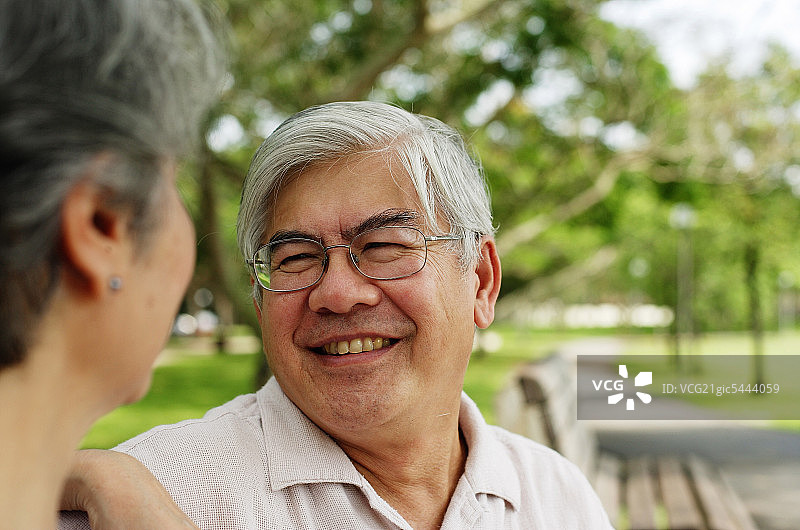 中年夫妇在公园里相对而坐，男人在微笑图片素材
