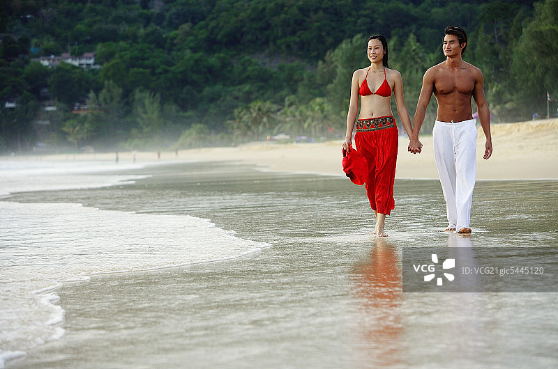 情侣手牵手在海滩上并肩行走图片素材