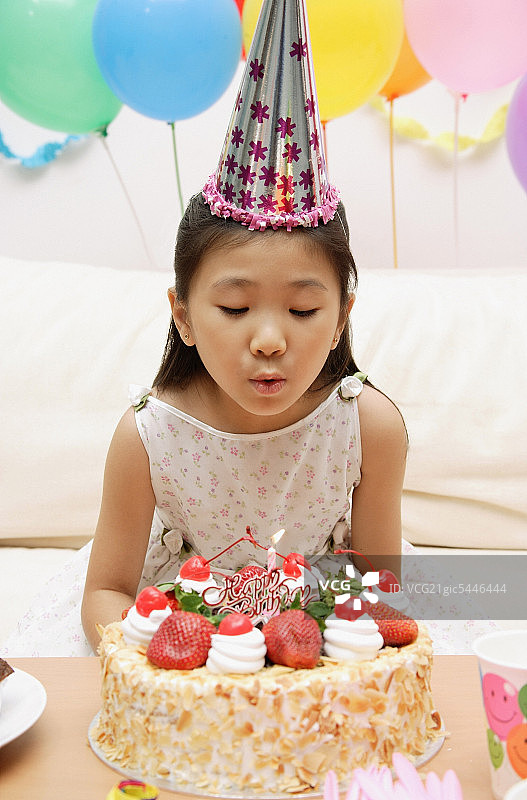 女孩吹灭蛋糕上的蜡烛图片素材