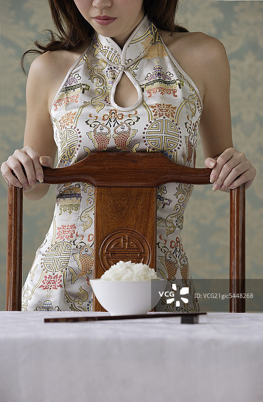 椅子后面的年轻女子，桌子上有碗米饭图片素材