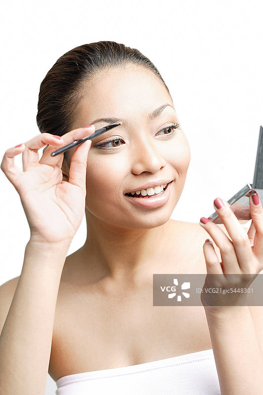 年轻女人使用眉刷，看向别处图片素材