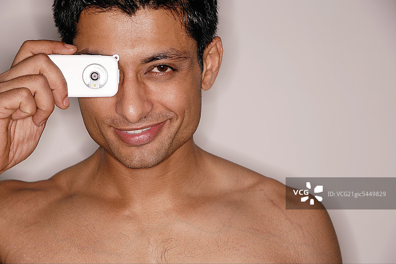 男人看着相机手机，面带微笑图片素材