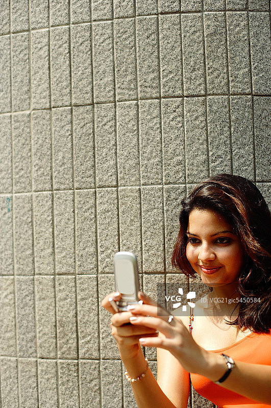 女人看着手机，面带微笑图片素材