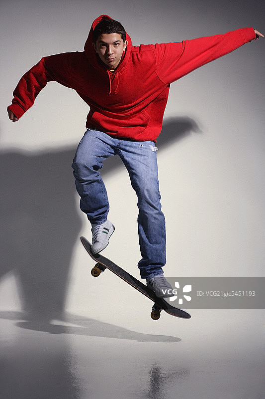 穿红色帽衫在滑板上的年轻男人图片素材