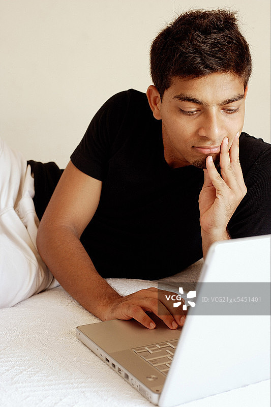 男人使用笔记本电脑，手托下巴图片素材