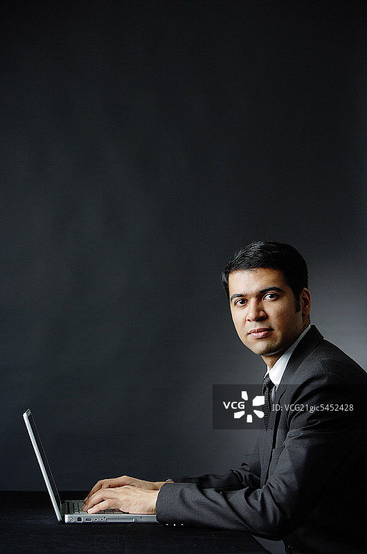 商人使用笔记本电脑，看着镜头，肖像照图片素材