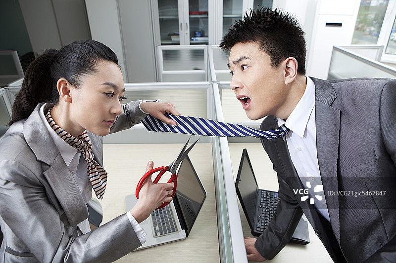 愤怒的女商人割断了商人的领带图片素材