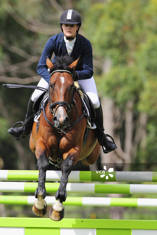 年轻女子骑马跳跃障碍图片素材