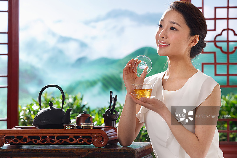 一个东方女孩在茶园的茶舍喝茶图片素材