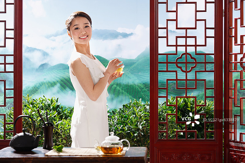 一个东方女孩在茶园的茶舍喝茶图片素材