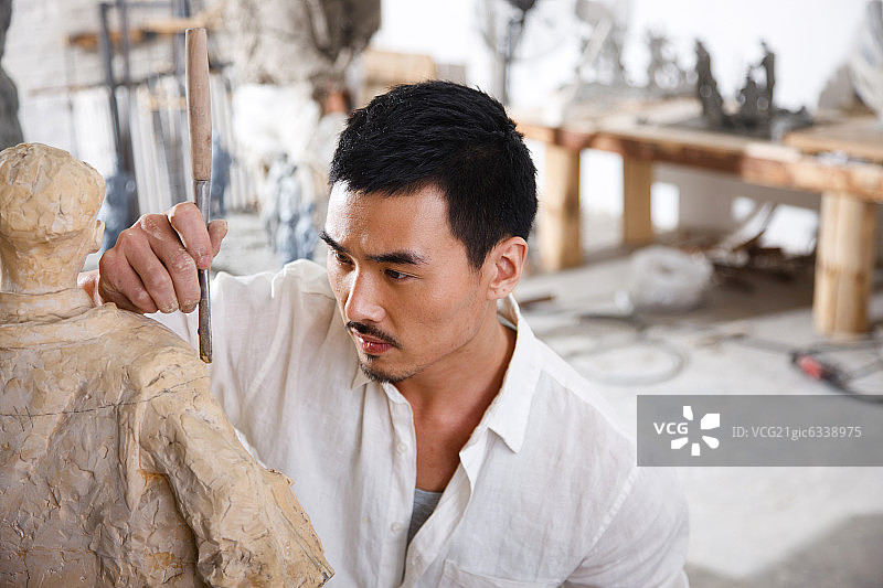 一个男雕塑家在工作室里创作图片素材