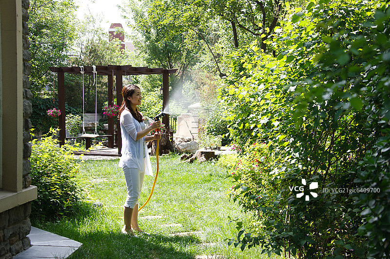 一个东方女人户外浇花图片素材