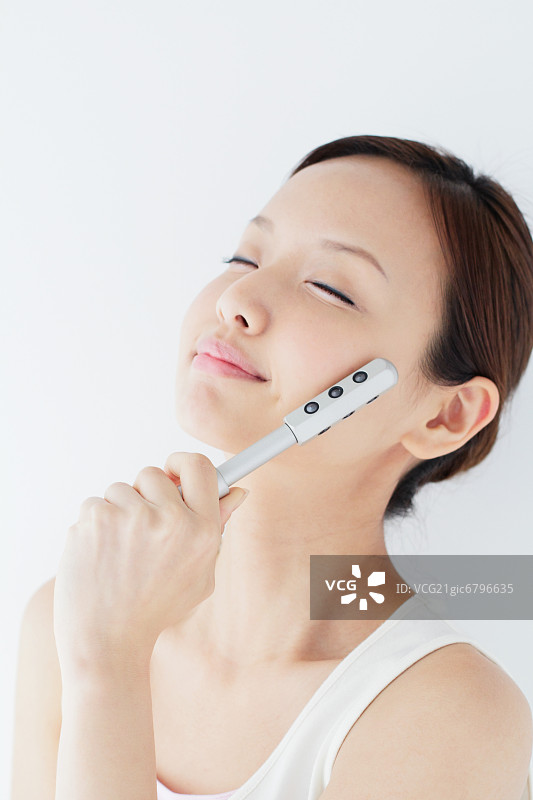 用美容棒按摩脸部的日本女人图片素材