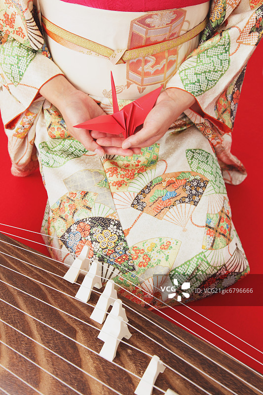 日本女人身穿和服，手持千纸鹤， рядом с 古筝的特写图片素材