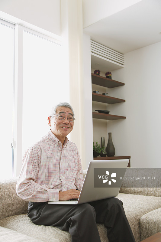 年长的男人在客厅沙发上使用电脑图片素材
