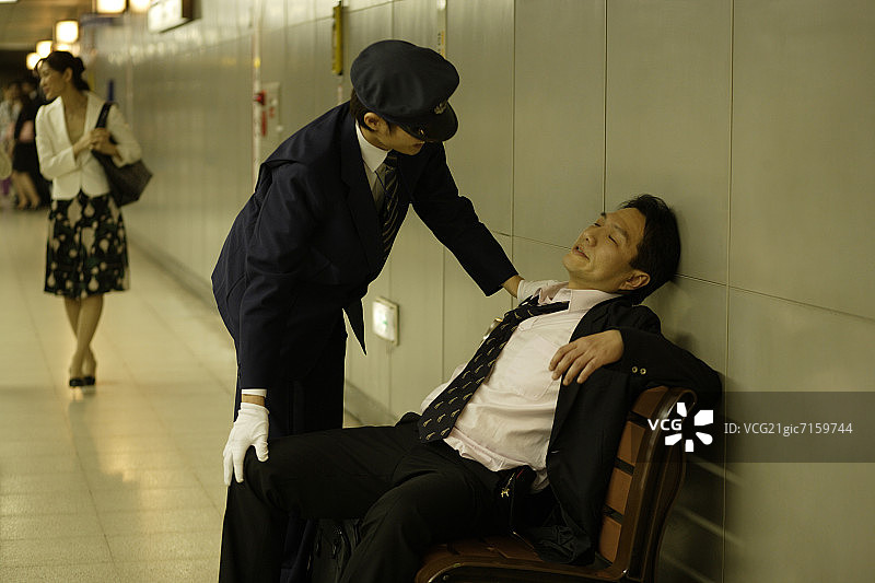 列车员与坐在站台长椅上的醉酒商人交谈图片素材