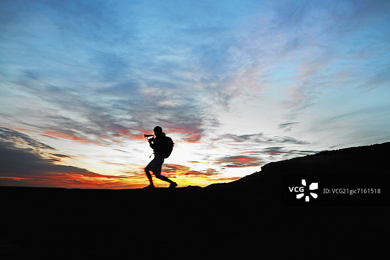 男人在日落时于车顶吹奏军号图片素材