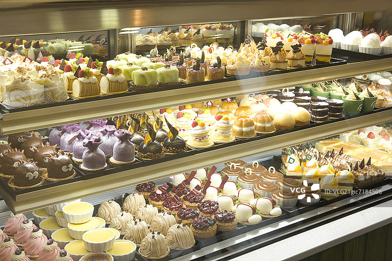 面包店展示柜中摆放着各种甜点图片素材