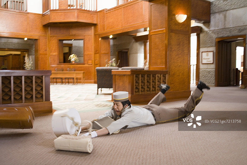酒店搬运工在酒店大堂绊倒，高角度视角图片素材